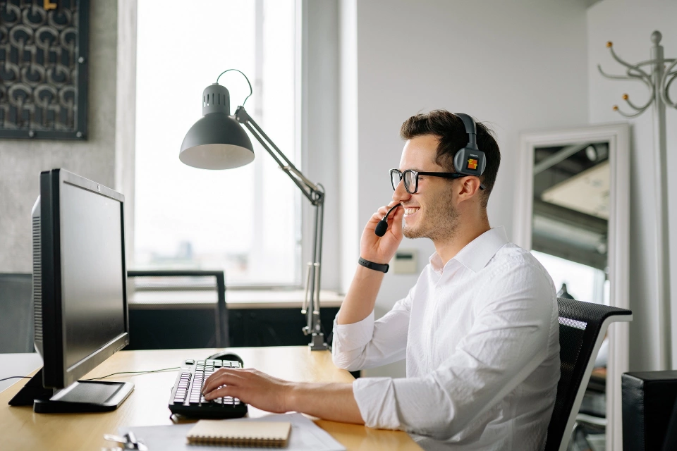 Lächelnder Mann mit Headset am Computer Lächelnder Mann mit Headset am Computer